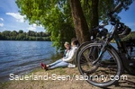 Zwei Frauen mit ihren Rädern machen eine Pause am Seeufer